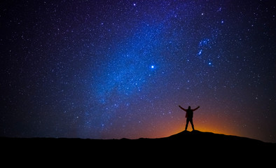 Man in front of the universe with his arms raised