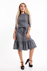 Attractive girl in a dress against a white wall