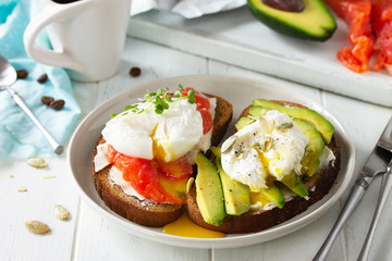Morning breakfast. Poached egg boiled sandwich with avocado, salmon and coffee on a wooden table.