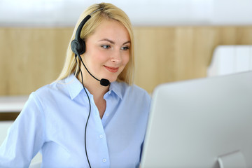 Call center. Blonde business woman sitting in headset at customer service office. Concept of...