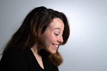 Side view of smiling attractive young brunette woman looking to the side over white background. Emotions in female face...