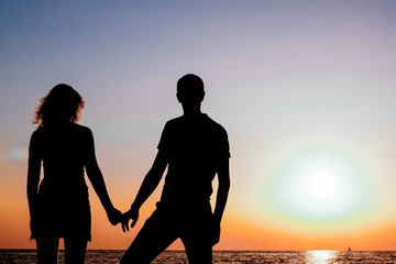 silhouette of a man and a woman by the sea at sunset