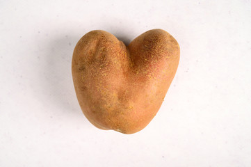 Obraz premium Ugly potato in the shape of a heart on a gray background. Funny, ugly vegetables.