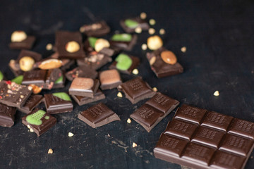 A variety of chocolate pieces lies on a black background. Raw food sweets, vegans, vegetarian and sugar free, handmade chocolates