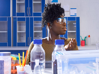 Young African female tech or scientist in protective glasses works with biological or medical...