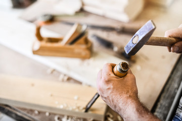 Worker hands use a wood chisel to decorate a board. Carpenter work in action.