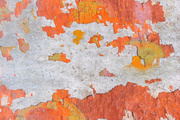 Old orange paint peels off the concrete wall. Grunge rough wall texture background.