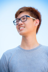 Low angle shot handsome Asian teenage boy wearing glasses, Portrait cheerful hipster young man smile with a happy face in Thailand