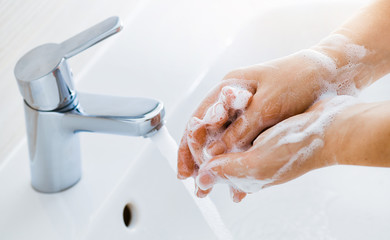 Woman use soap and washing hands under the water tap. Hygiene concept hand detail.