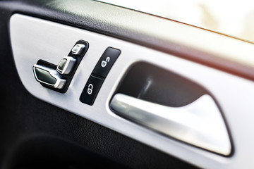 Car interior details of door handle with windows controls buttons and adjustments. Luxury close up or car window controls system.