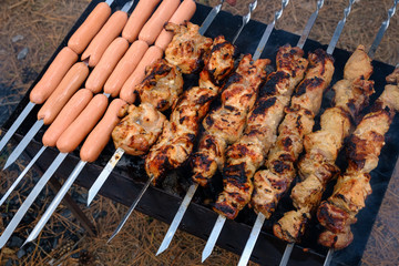 Preparation of shish kebab and sausages on outdoor charcoal grill