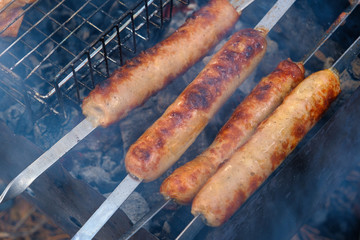 Preparation of sausages on outdoor charcoal grill