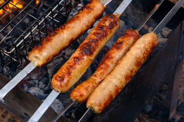 Preparation of sausages on outdoor charcoal grill
