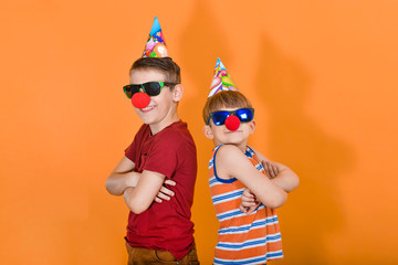 Two boys with a clown nose in sunglasses will put their hands together at the chest and stand with...