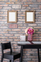Pair of identical picture frame mockups hanging on the brick wall above the breakfast table.