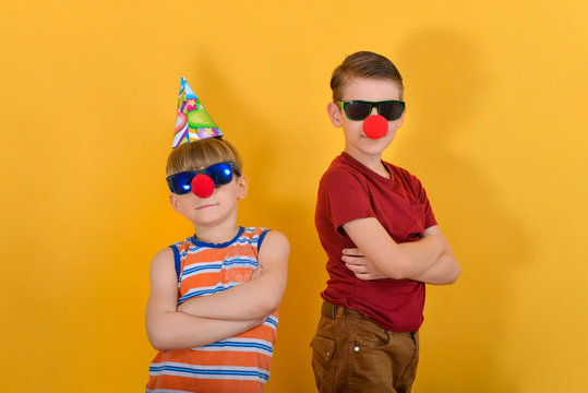 Two boys with a clown nose in sunglasses will put their hands together at the chest and stand with their backs to each other.