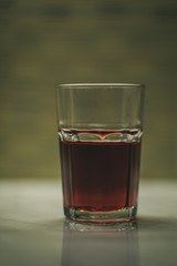 glass with half full red juice drink