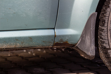 Rust on the body of a blue car. Rust hole on old worn painted metal surface. Corrosion of the vehicle metal due to accident