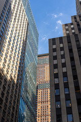 Fototapeta na wymiar Detail close up of a glass skyscraper in Manhattan, New York City, close tu sunset on a sunny day. Black blue yellow and orange hues