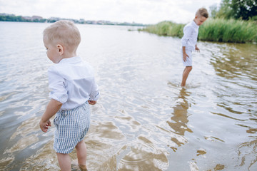 Two little brothers walking on a sandy beach near the water