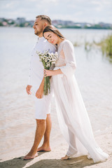 Fototapeta na wymiar Beautiful young couple in white clothes romantically walking on the beach.