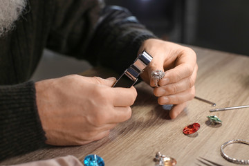 Fototapeta premium Jeweller examining adornment in workshop, closeup