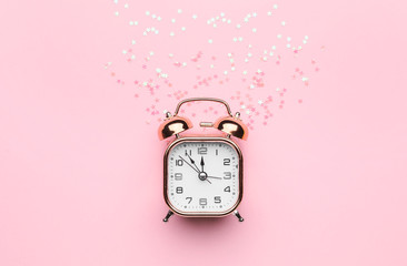 Alarm clock with confetti on color background