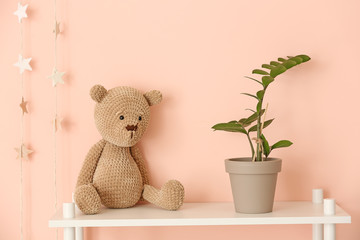 Cuddly toy with houseplant on table in children's room