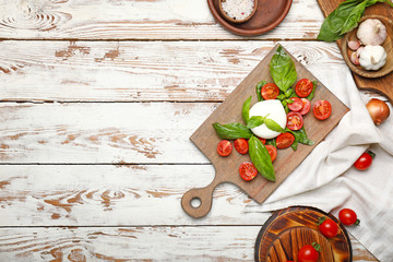 Mozzarella cheese with tomatoes and basil on white table