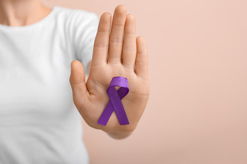 Woman with violet ribbon on color background, closeup. Domestic violence concept
