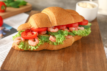 Tasty croissant sandwich on wooden board