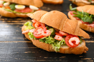 Tasty croissant sandwich on wooden table