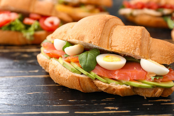 Tasty croissant sandwich on wooden table
