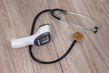 Termometr elektroniczny i stetoskop lekarski leży na stole. Przedmioty lekarskie pomagające w walce z epidemią wirusa.
