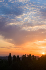 Landscape with dramatic light - beautiful golden sunset with saturated sky and clouds.