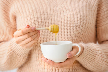 Woman drinking tea with honey, closeup