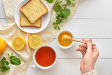 Woman drinking tea with honey at table, top view