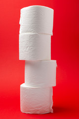 Symbol image for corona crisis panic buying / hoarding. Pile of toilet paper on red Background,...