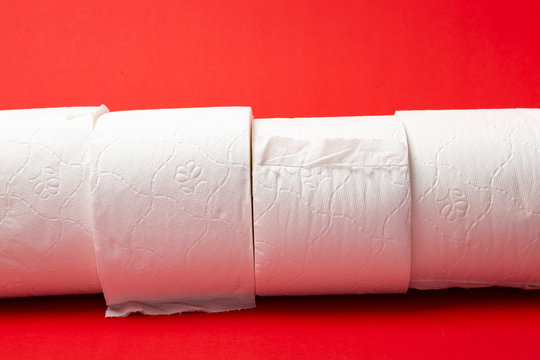 Symbol image for corona crisis panic buying / hoarding. Rolls of toilet paper on red Background, with copy space.