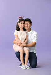 Happy Asian man and his little daughter on color background