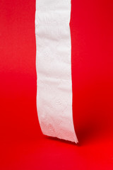 Symbol image for corona crisis panic buying / hoarding. Roll of toilet paper on red Background,...
