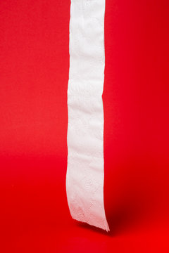 Symbol image for corona crisis panic buying / hoarding. Toilet paper on red Background, with copy space.