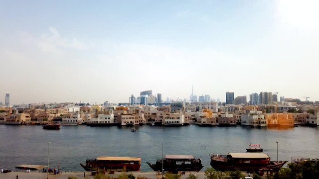 Traditional wooden boats on old Dubai Creek with downtown view in the background time lapse