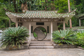 Guilin, China - May 11, 2010: Seven Star Park. Pavilion with circular doorway set in white wall...
