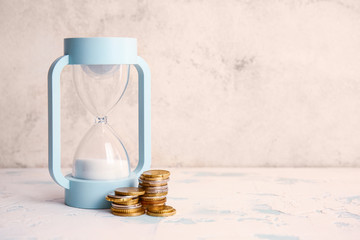 Hourglass and coins on table. Time management concept