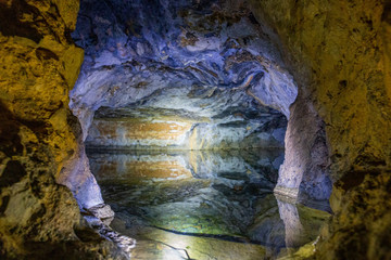 A cave with colorful walls and a tank full of water.