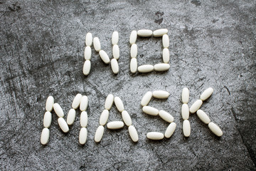 The inscription English, laid out in white oval tablets on a gray textural background - no mask. The concept of a shortage of medical masks. The epidemic of coronavirus