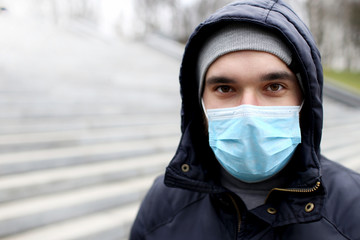 Fototapeta na wymiar Closeup portrait outdoors of a man in a medical mask who is sick with a virus. Epidemic. Coronovirus