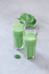 Vegan spinach smoothie drink in a glass on a light background