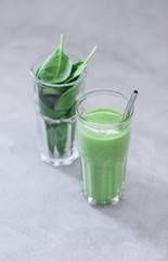 Spinach smoothie in a glass on a light background